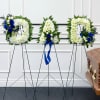 Three funeral wreaths on stands beside a casket
