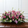 Large pink and white floral casket spray on a polished coffin