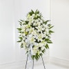 White floral standing spray on an easel with a ribbon