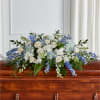 White and blue floral casket spray with roses and hydrangeas