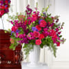 Large bouquet of pink and purple flowers in a white pedestal vase