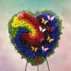 Heart-shaped floral wreath with rainbow flowers and butterfly accents on a stand