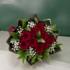 Bouquet of red roses with white baby's breath and green leaves wrapped in black paper