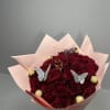 Bouquet of red roses wrapped in pale pink paper with gold chocolates and butterfly picks