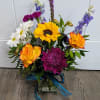 Glass vase includes Roses, Mums, Sunflower, Daisies, Larkspur, carnations and a variety