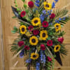 Standing Spray Includes, Red Roses, Blue Delphinium, Sunflowers and Bells of Ireland