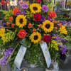 Casket spray includes Red and Orange Roses, Sunflowers, Carnations, Stock, Bells of