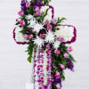 Cross-shaped floral tribute with pink roses, white chrysanthemums, and purple orchids