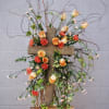 Floral cross arrangement with peach roses and orange carnations