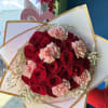 Bouquet of red roses and pale pink carnations wrapped in white paper