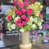 Pink roses and green orchids arranged in a gold vase