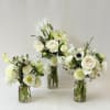 Three white floral arrangements in clear glass vases