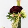 Tall floral arrangement with burgundy blooms, pale orchids, and a clear vase
