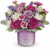 Pink and lavender flowers arranged in a glittery vase