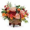 Arrangement of peach and orange roses with mixed flowers in a low wooden container