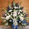 White lilies and chrysanthemums with blue ribbon on a sympathy spray