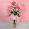 Pink roses in a clear glass vase with baby's breath and a pink bow
