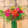 Bright mixed bouquet in a tall glass vase with pink, orange, and yellow blooms