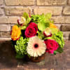 Bright mixed bouquet in a glass vase with roses, orchids, and a gerbera daisy