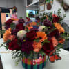 Colorful mixed flower arrangement in a rainbow basket with butterfly picks