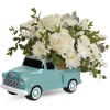 White roses and daisies arranged in a turquoise truck planter