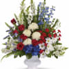 Large red, white, and blue floral arrangement in a white vase