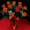 Bouquet of orange and yellow roses in a glass vase with red ribbon