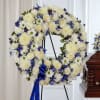 White and blue floral wreath on a stand with a blue ribbon