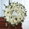 White floral wreath on a stand displayed over a casket