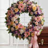 Heart-shaped floral wreath with pink and peach flowers on a stand