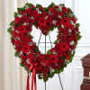 Heart-shaped red rose and gerbera wreath on an easel with a ribbon
