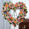 Heart-shaped floral spray on an easel beside a casket