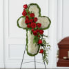 Cross-shaped floral tribute with red roses and white blooms on a stand