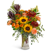 Bouquet of sunflowers, orange roses, and carnations in a clear glass vase