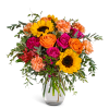Bouquet of sunflowers, roses, and carnations in a clear glass vase