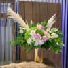 Pink and white floral arrangement in a gold vase with pampas grass