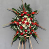 Standing floral spray with red roses, white lilies, and daisies on an easel