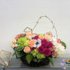 Mixed bouquet of roses, hydrangeas, and white blooms in a low basket