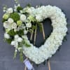 Heart-shaped floral wreath with white flowers and green accents on an easel