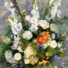 Large mixed floral arrangement with white, purple, and orange blooms
