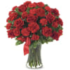 Red roses and carnations in a clear glass vase with a red ribbon