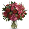 Bouquet of pink lilies and red roses in a clear glass vase