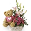Teddy bear in a basket with pink flowers and lilies