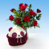 Red roses in a glass vase with a panda plush in front