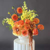 Orange and yellow floral arrangement in a white vase