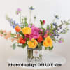 Colorful mixed bouquet in a clear glass vase with a striped ribbon