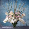 White orchids and pale pink roses in a clear rectangular vase