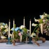 Three floral arrangements with white calla lilies and candles on driftwood bases
