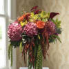 Bouquet of pink hydrangeas, orange roses, and calla lilies in a glass vase