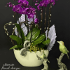 Purple orchids arranged in a white bowl with decorative bird figurines